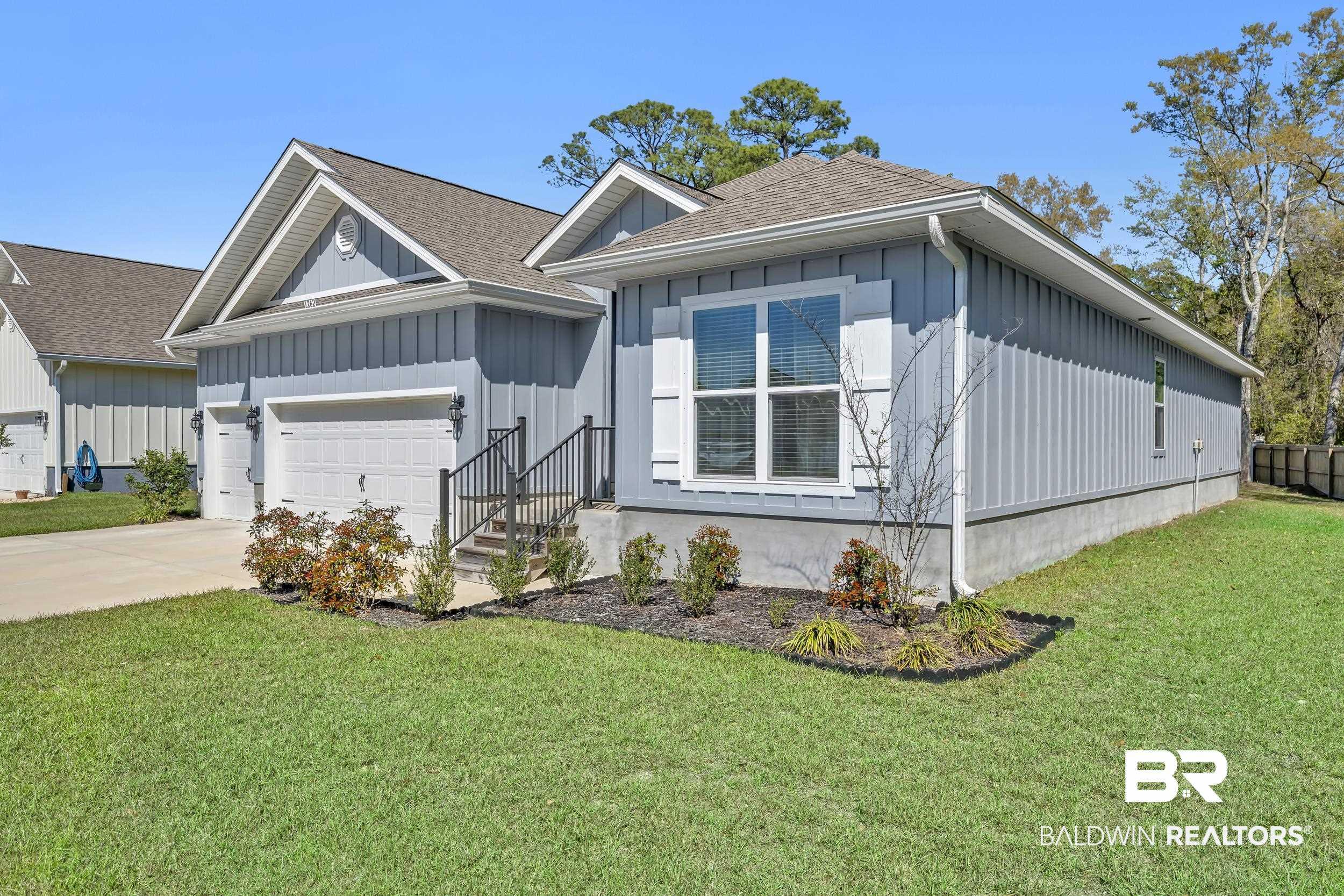 Image 4: View of front of house featuring roof with shingles, a front yard, driveway, an attached garage, and board and batten siding
