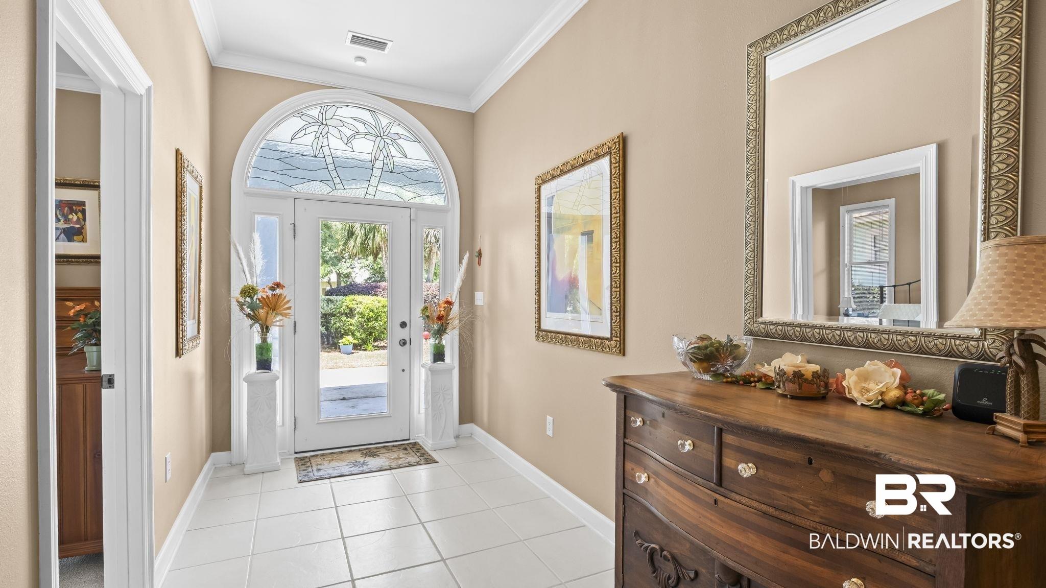 Image 3: Entryway featuring white tile flooring, crown molding, and a prominent arched transom window with decorative glass