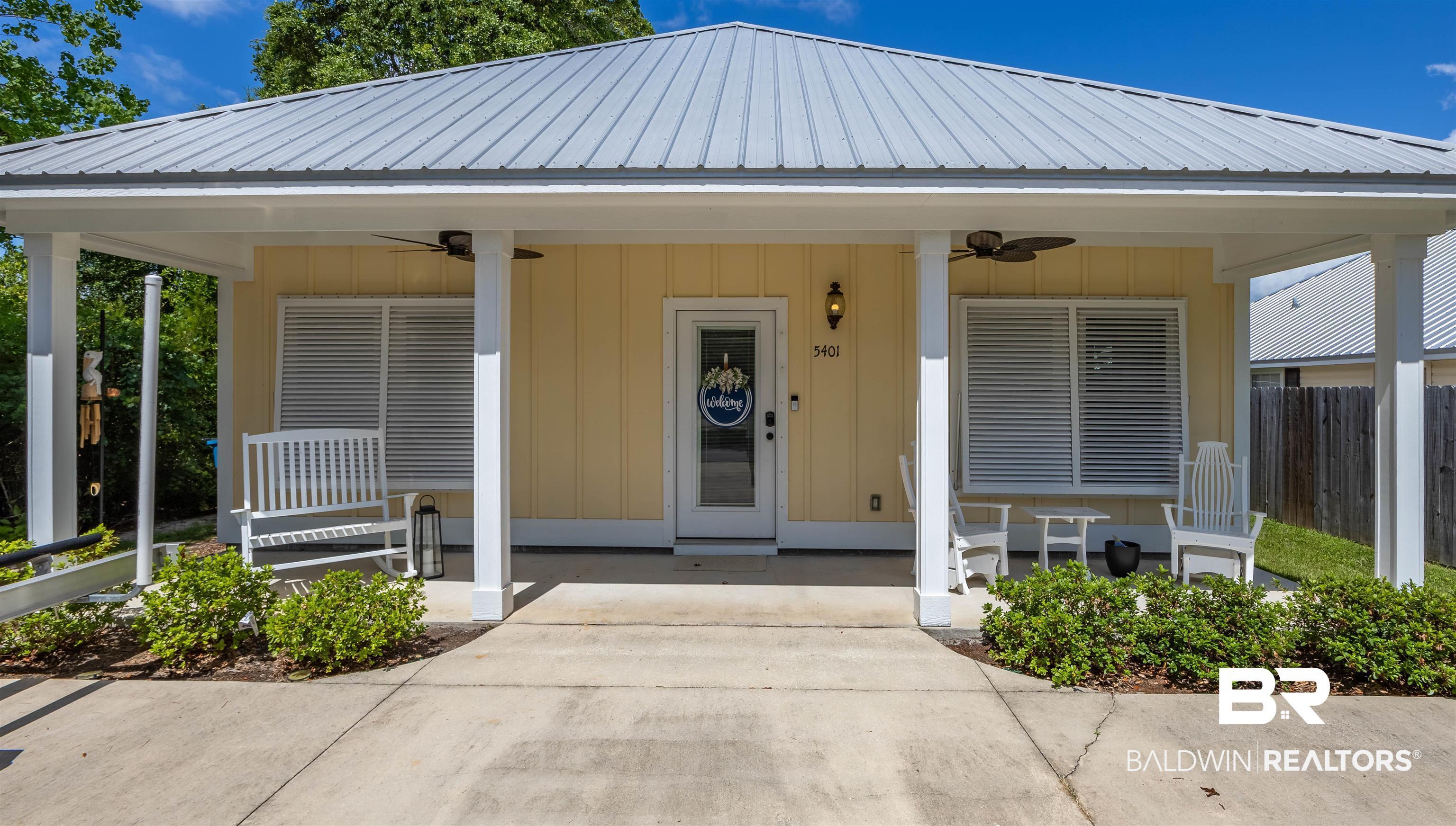 Image 1: Yellow exterior with white trim, featuring a corrugated metal roof and a covered front porch