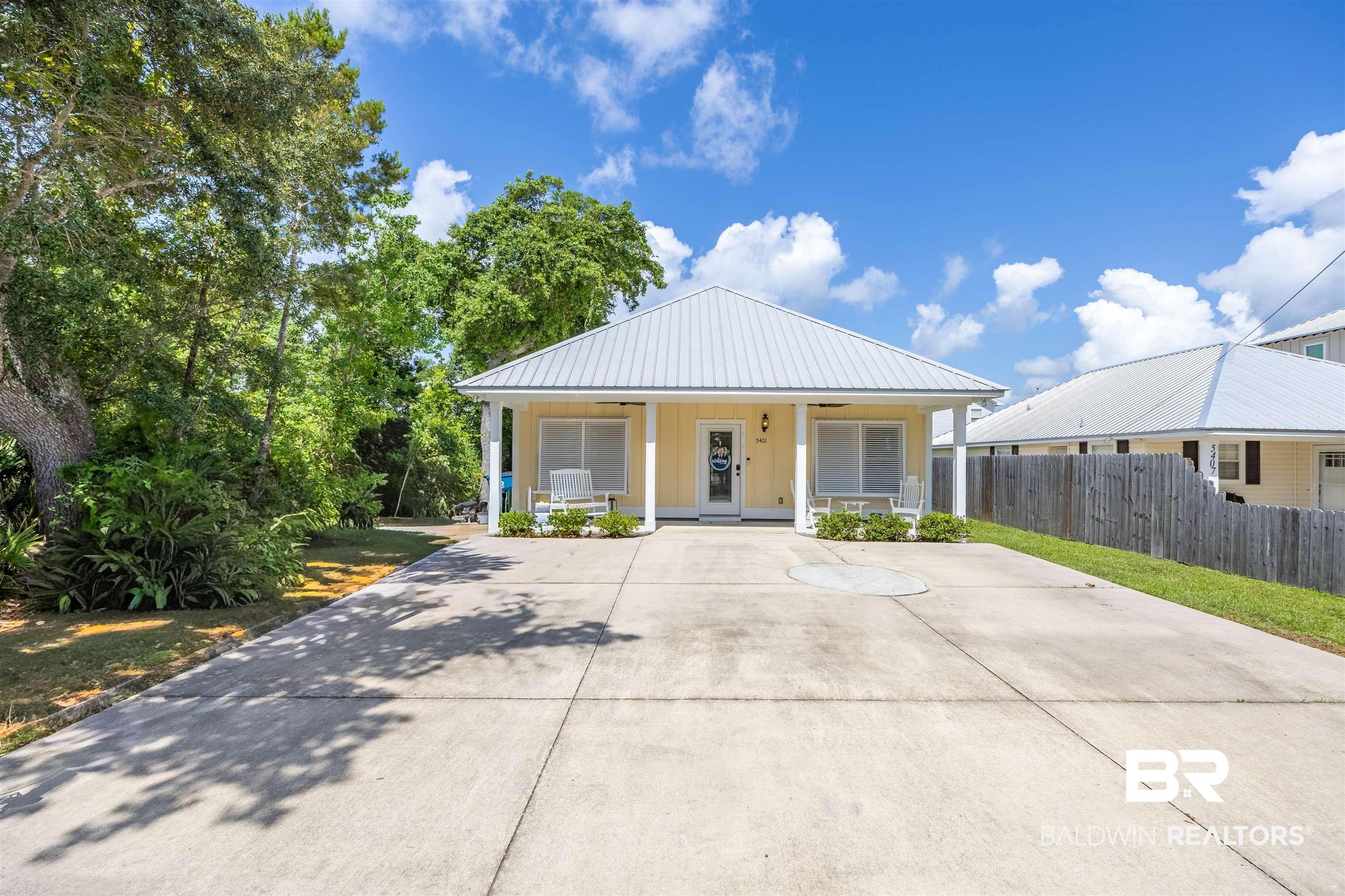 Image 3: Coastal-style residence featuring a pale yellow exterior and a prominent metal roof