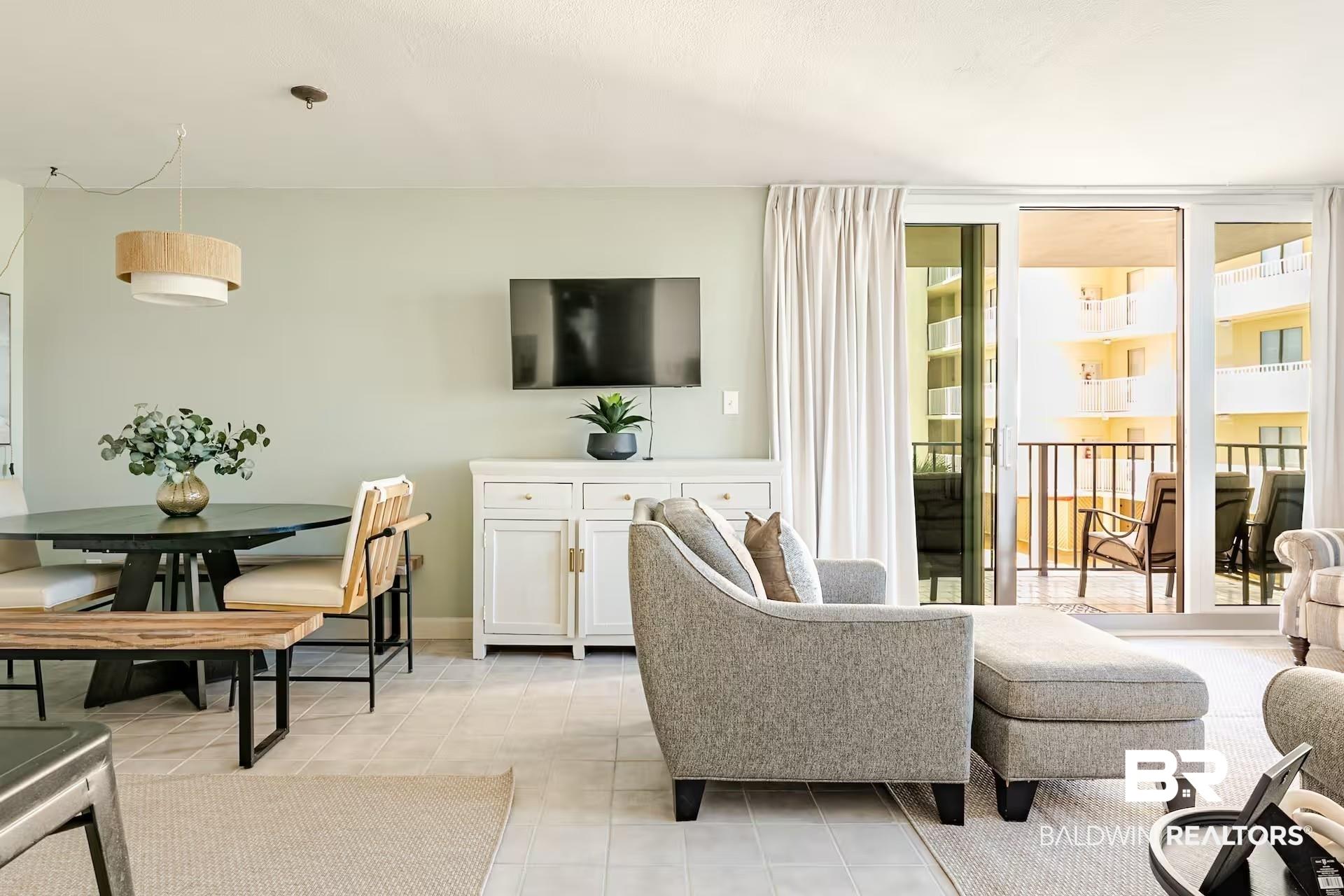 Image 3: Light-filled living space featuring neutral wall tones, tile flooring, and a built-in wall cabinet