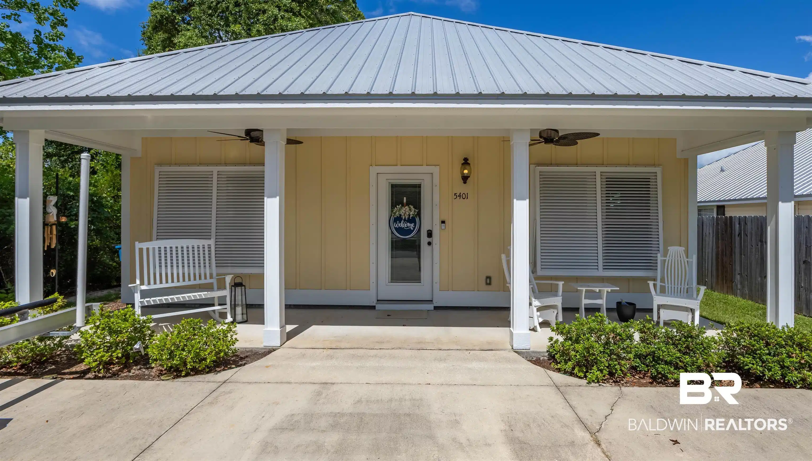 Image 1: Yellow exterior with white trim, featuring a corrugated metal roof and a covered front porch