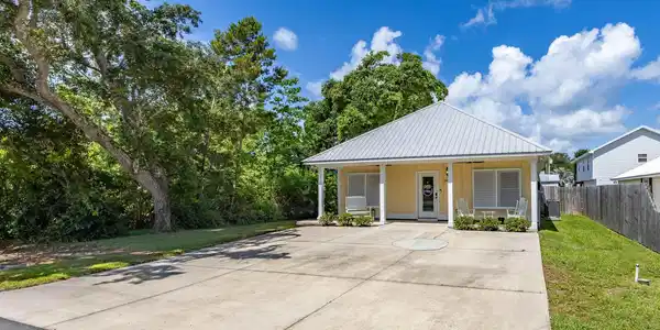 Image 2: Single-story residence featuring a light yellow exterior, a standing seam metal roof, and a covered front porch with white columns