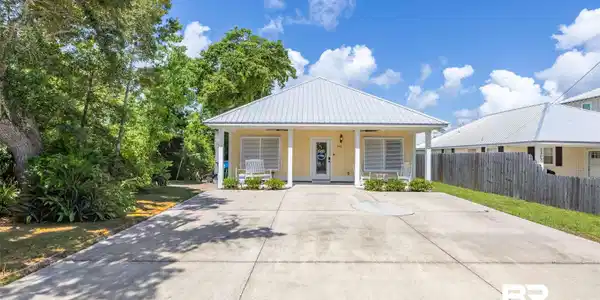 Image 3: Coastal-style residence featuring a pale yellow exterior and a prominent metal roof