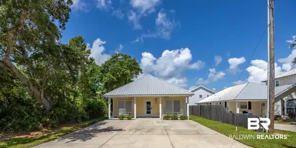 Image 4: Single-story residence featuring a pale yellow exterior and a silver metal roof