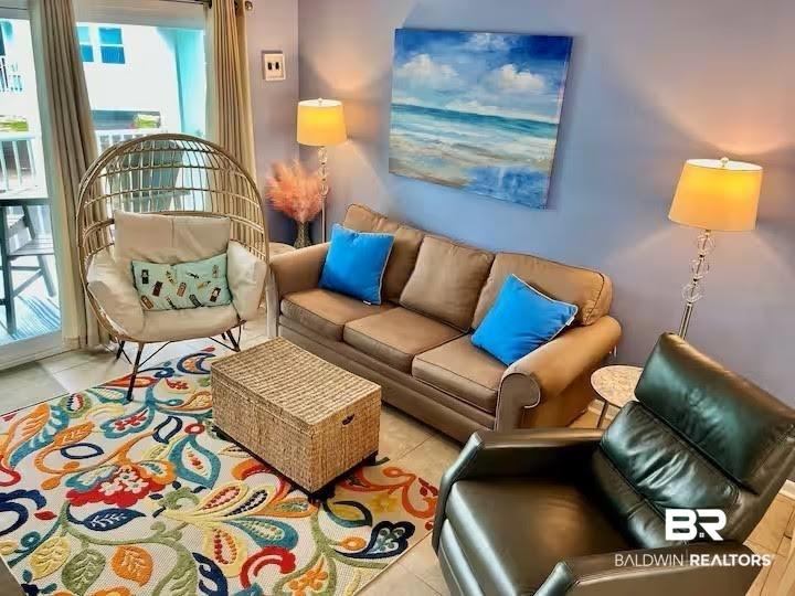 Image 2: Living area featuring tile flooring, a large area rug, and a sliding glass door providing access to an exterior balcony