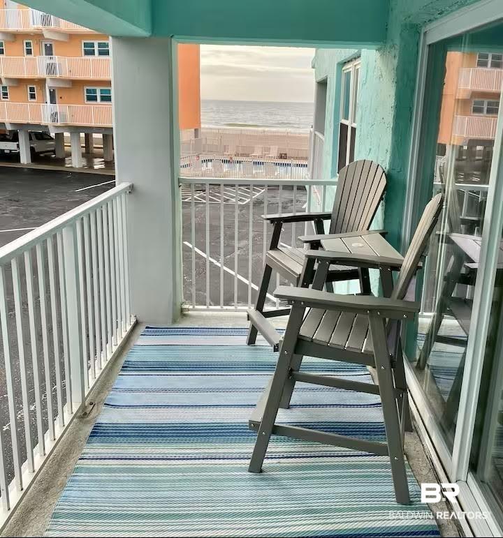 Image 4: Balcony featuring a partial ocean backdrop, white railing, and a sliding glass door