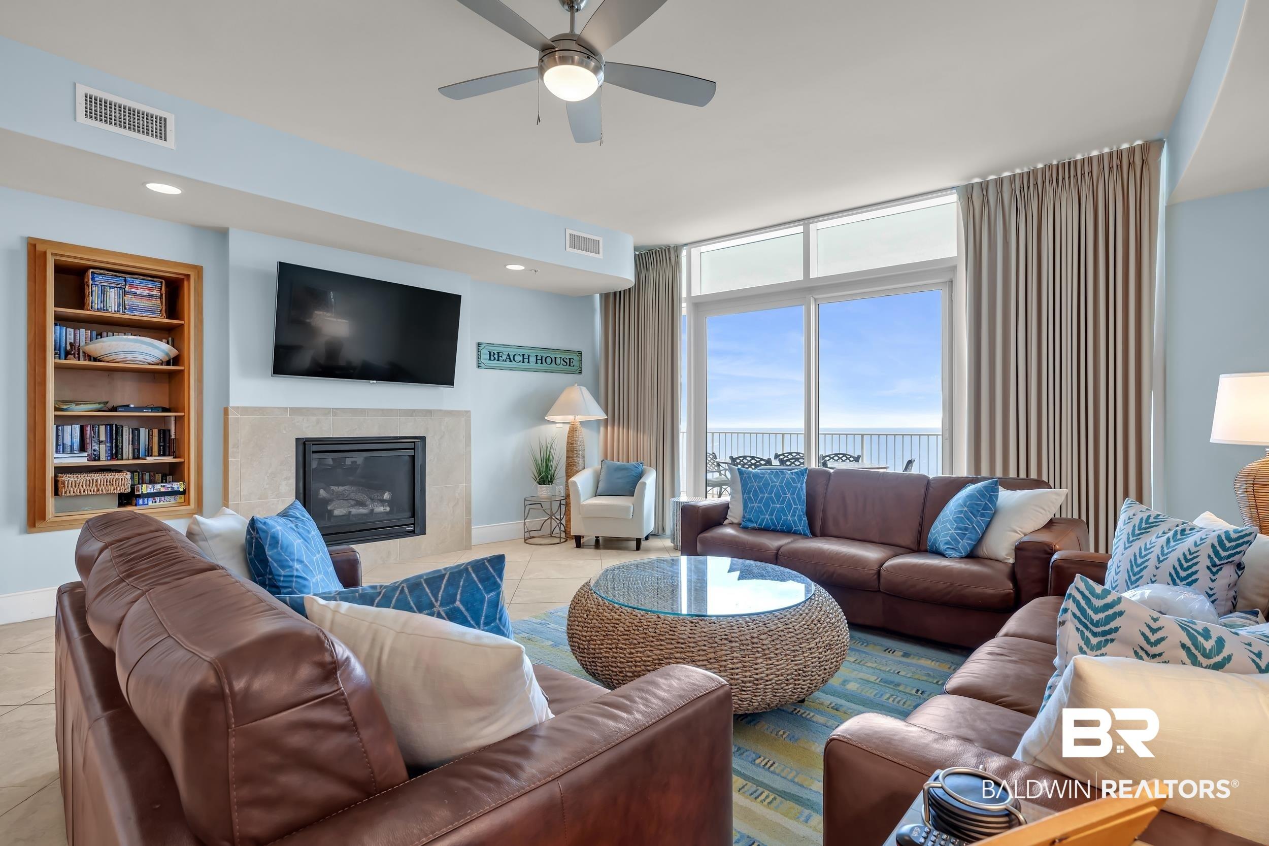 Image 4: Spacious living area featuring a built-in fireplace with stone surround, recessed lighting, and a ceiling fan