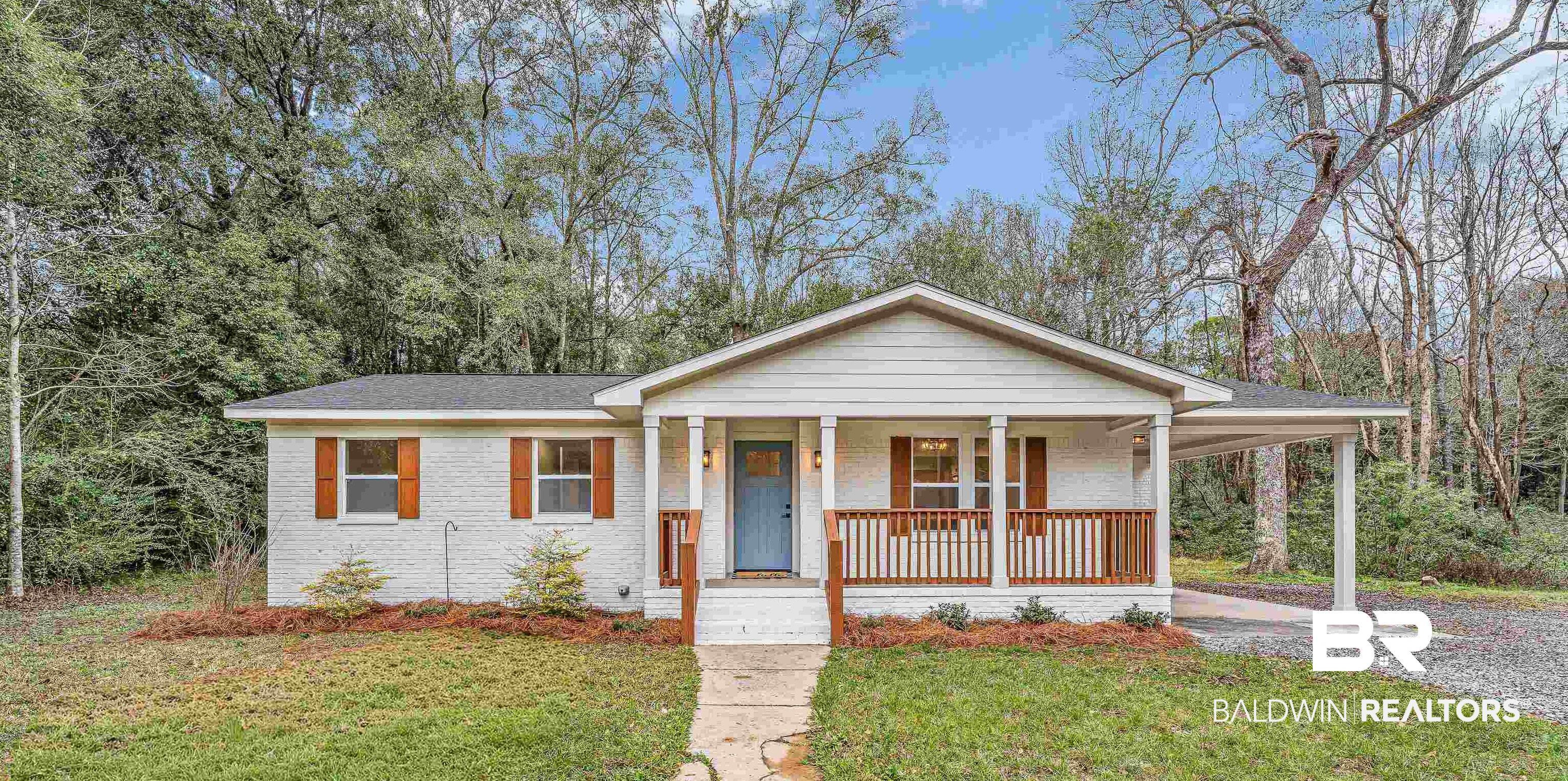Image 1: View of front of home featuring an attached carport, a front lawn, covered porch, brick siding, and gravel driveway