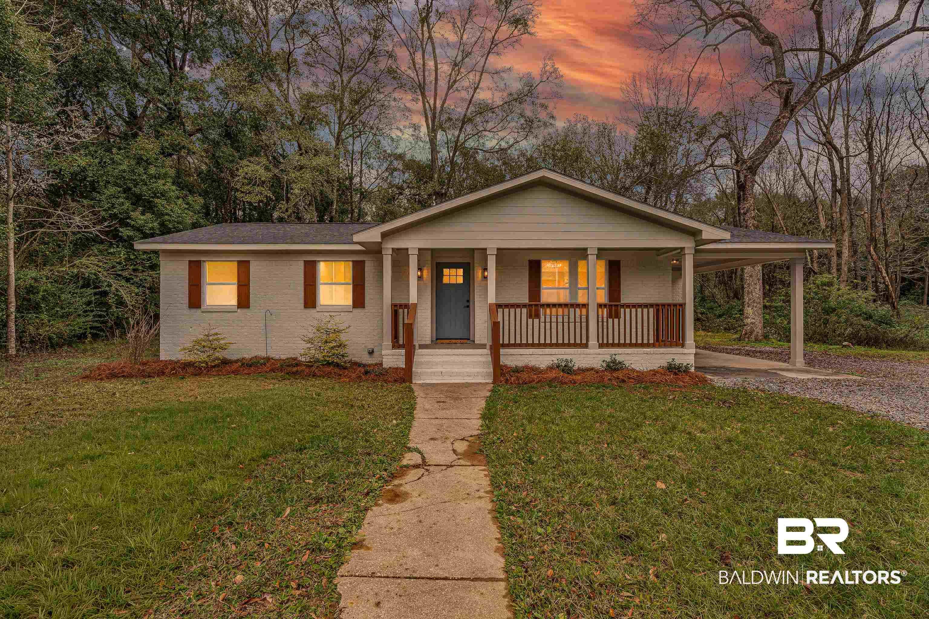 Image 2: View of front facade featuring an attached carport, a lawn, a porch, driveway, and brick siding