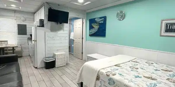 Image 2: Bedroom featuring wood walls, wood finish floors, freestanding refrigerator, a wainscoted wall, and a paneled ceiling