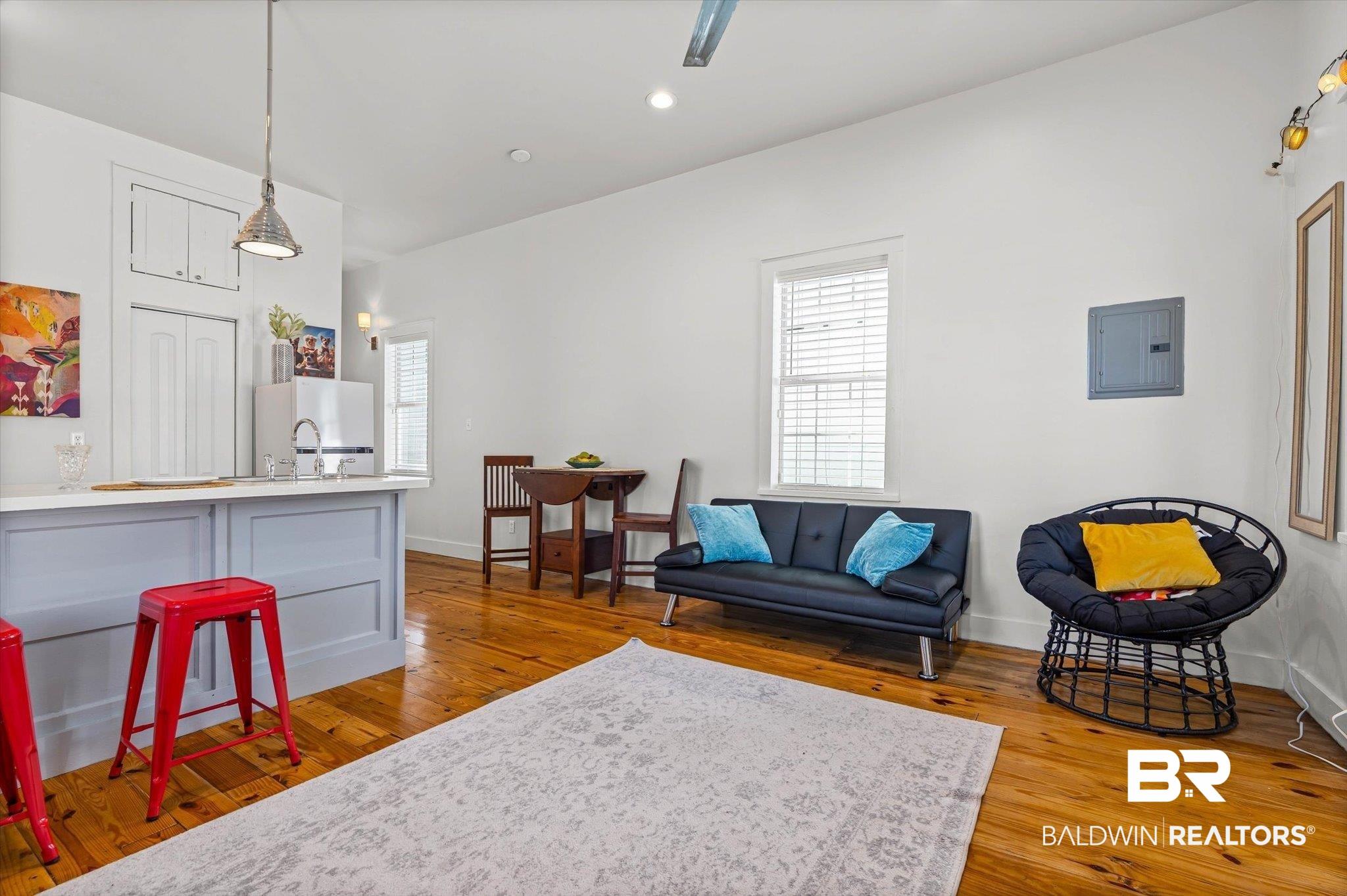 Image 3: Open-concept space featuring wood-finish flooring, white walls, and a light gray kitchen island with a white countertop