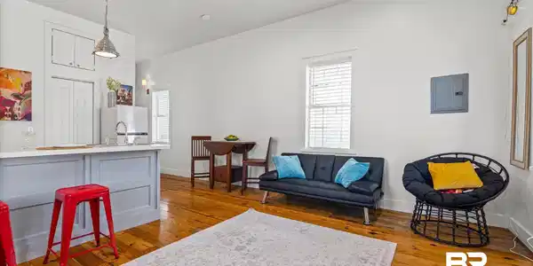 Image 3: Open-concept space featuring wood-finish flooring, white walls, and a light gray kitchen island with a white countertop