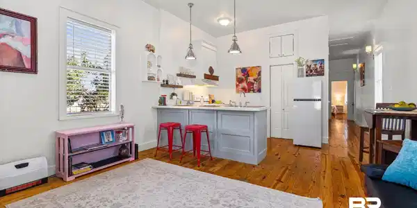 Image 4: Open-concept living space featuring wood-finish flooring, recessed lighting, a kitchen island with seating, and a large window providing natural light