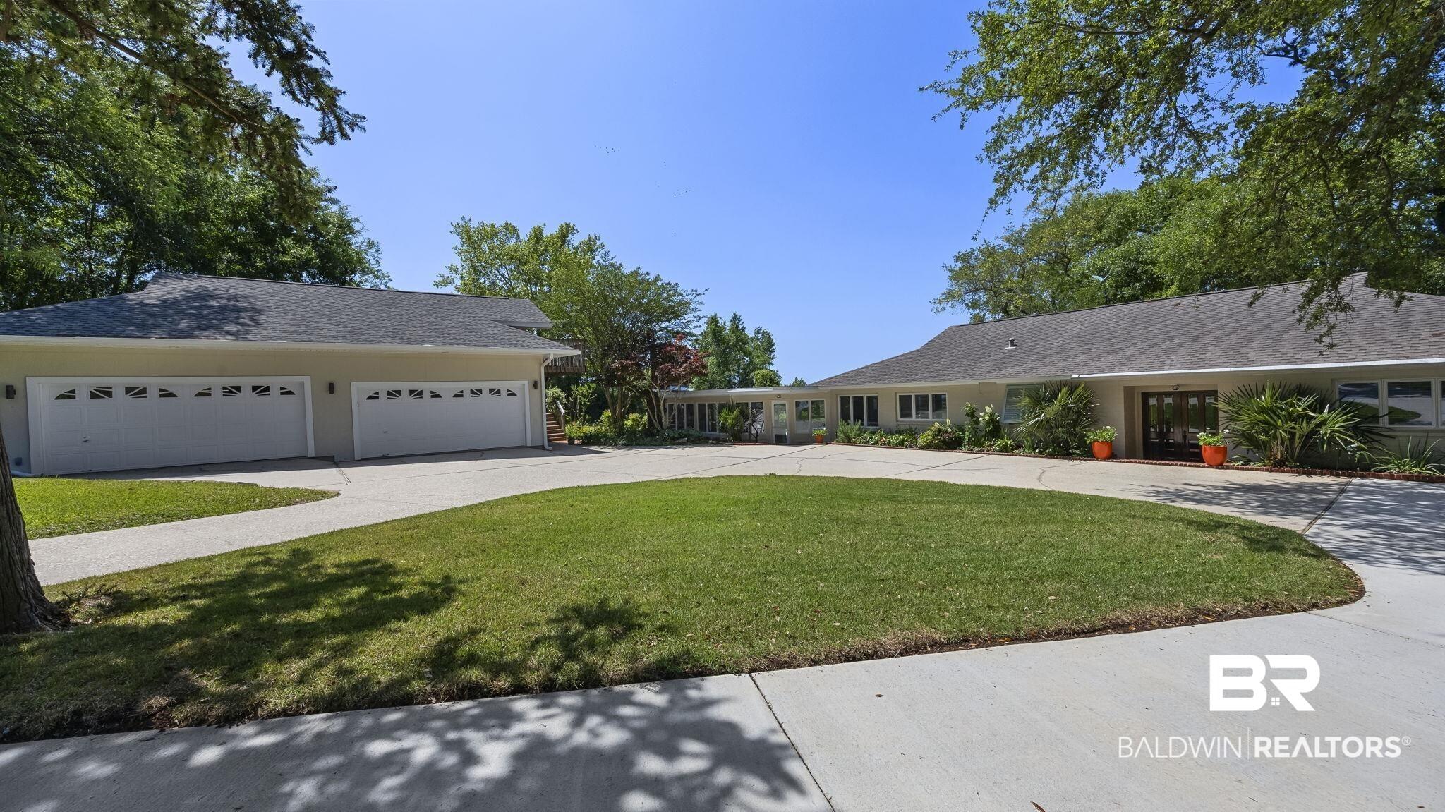 Image 2: Expansive circular driveway providing access to a four-car garage with individual doors