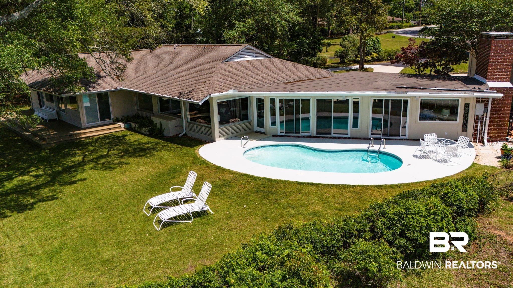 Image 3: Exterior featuring a kidney-shaped swimming pool with surrounding hardscaping, an expansive lawn, and mature trees