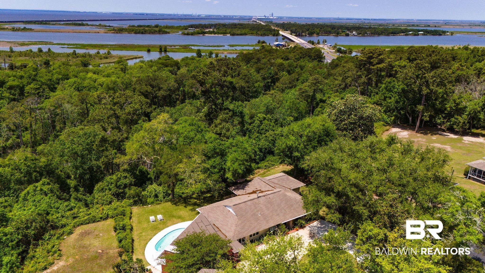 Image 4: Residence featuring a private outdoor pool with a surrounding patio, mature trees, and extensive landscaping