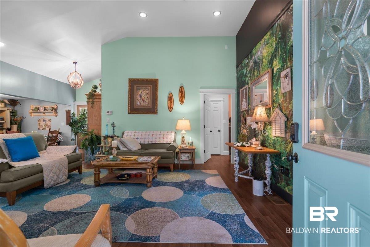 Image 2: Entryway featuring a decorative aqua door with etched glass, dark wood-finish flooring, and a bold accent wall with nature-inspired wallpaper
