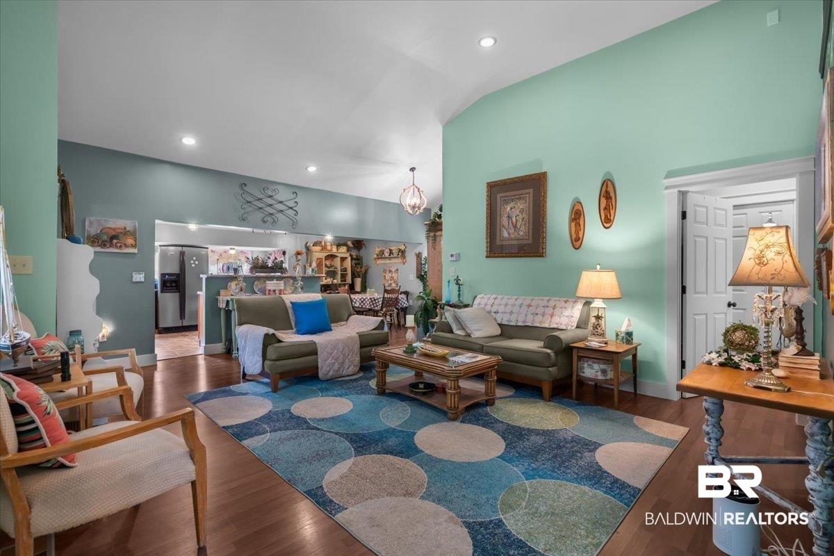 Image 3: Vaulted ceilings enhance this living space featuring recessed lighting and wood-finish flooring