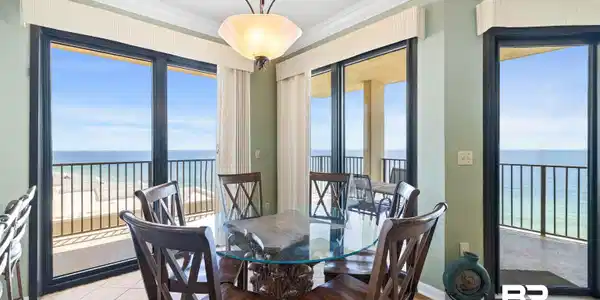 Image 4: Spacious dining area featuring multiple sliding glass doors opening to outdoor balconies