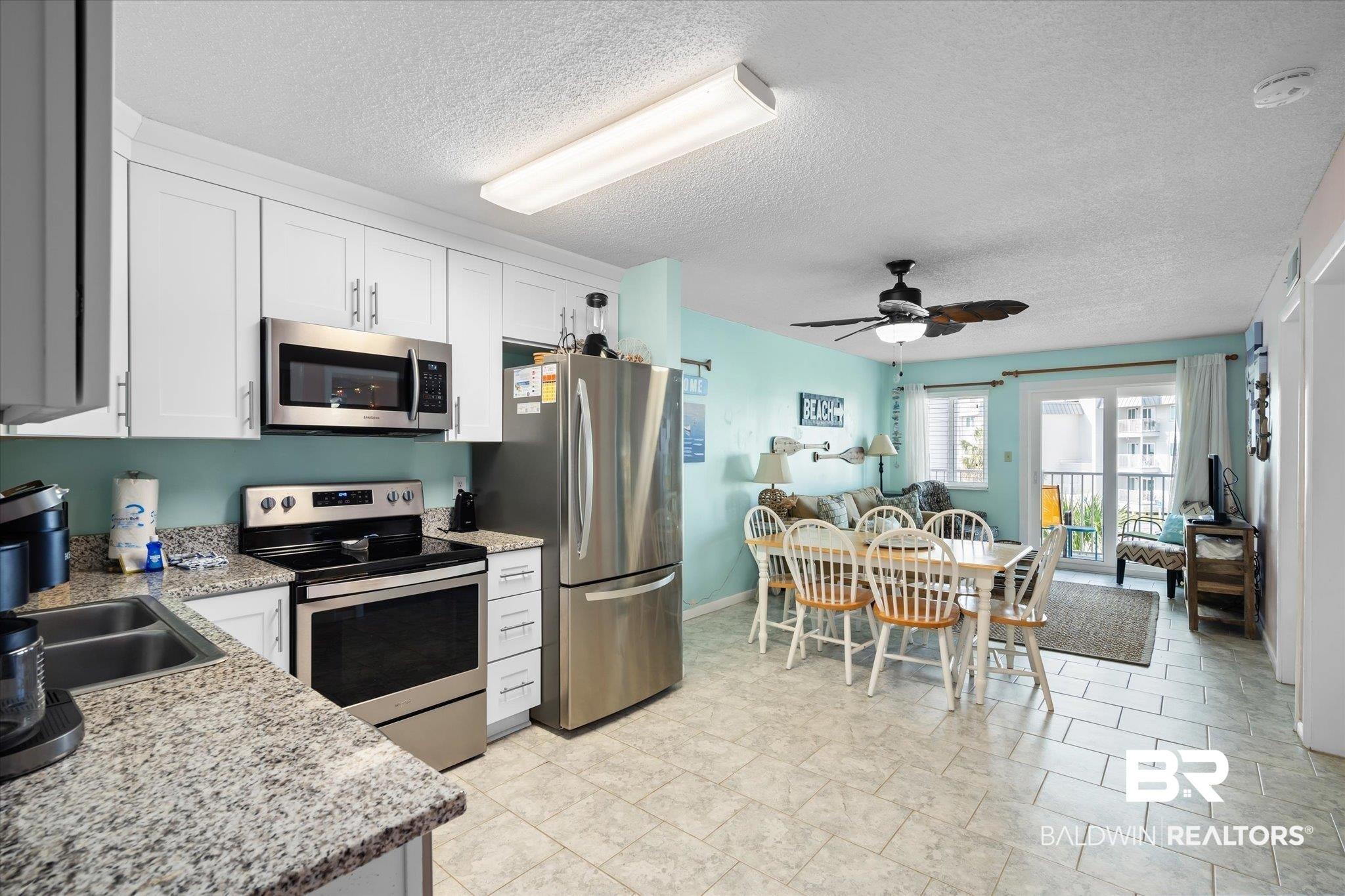 Image 3: Kitchen with a textured ceiling, white cabinetry, stainless steel appliances, and ceiling fan