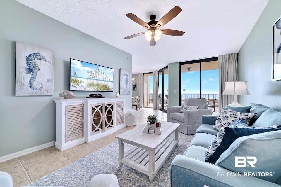 Image 2: Living room featuring a wall of windows, light tile patterned floors, and ceiling fan