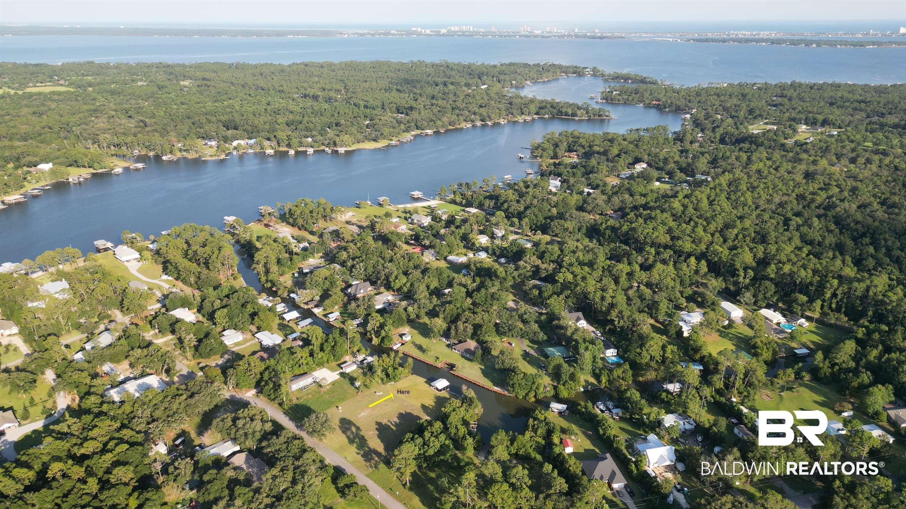 Image 1: Aerial view of property's location featuring a forest and a nearby body of water