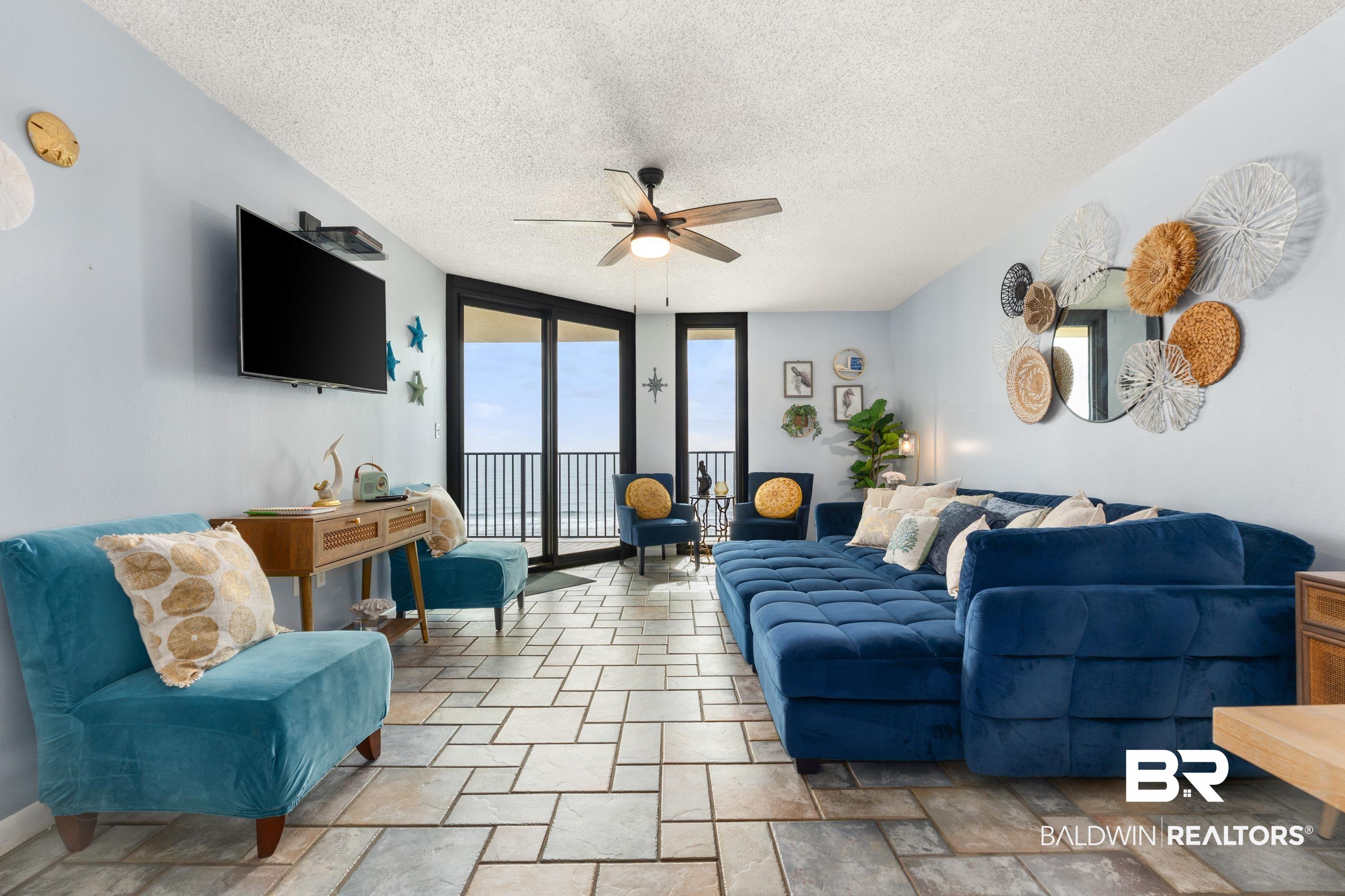 Image 2: Living room featuring floor to ceiling windows, a textured ceiling, ceiling fan, and light stone finish flooring