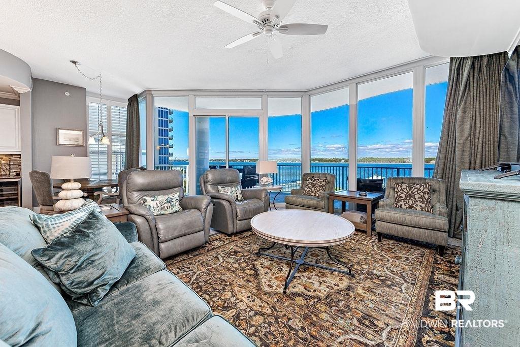 Image 2: Living area with expansive windows, ceiling fan, and a textured ceiling