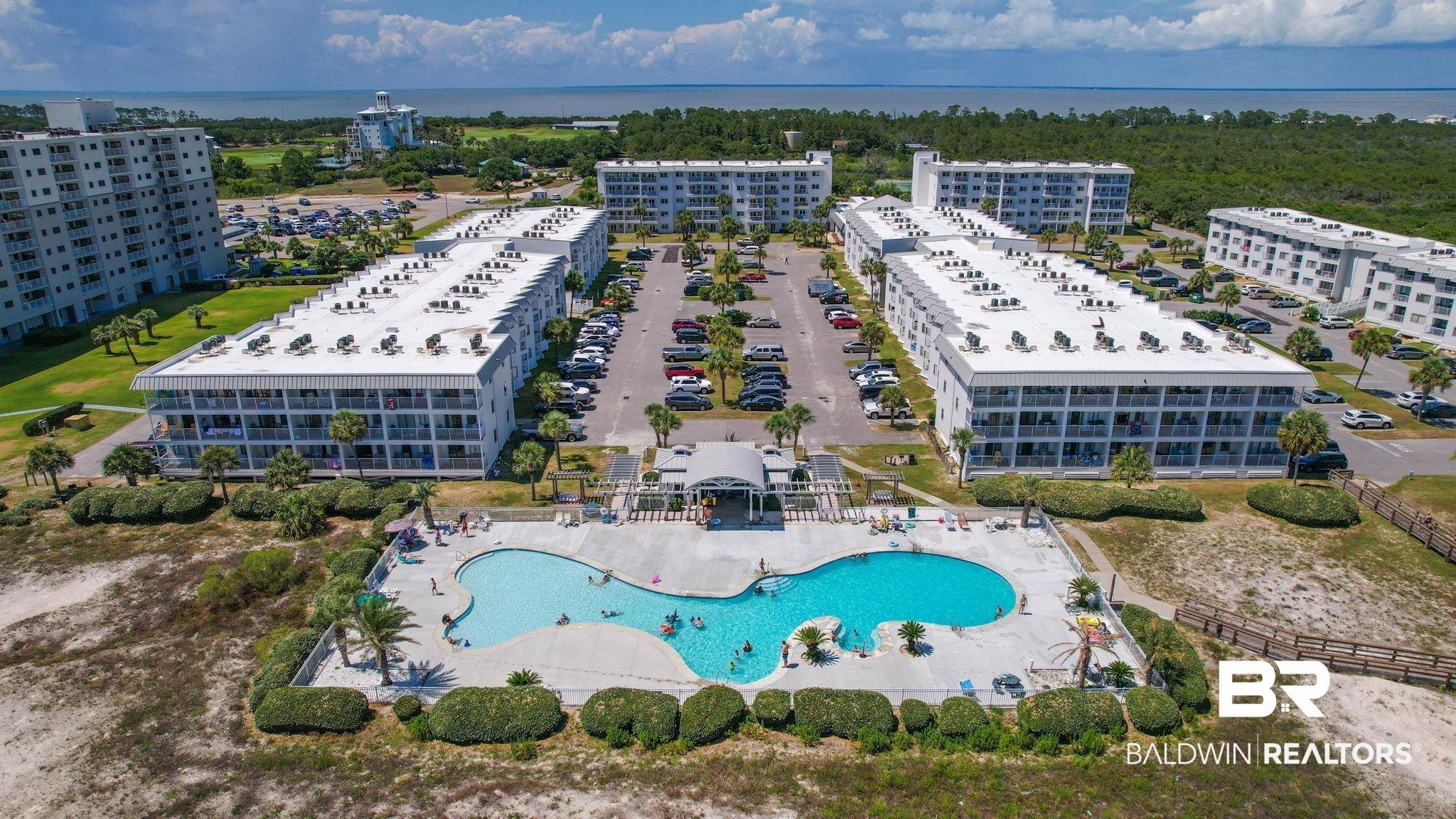 Image 1: Resort-style pool with a distinct freeform shape, surrounded by paved decking and mature landscaping