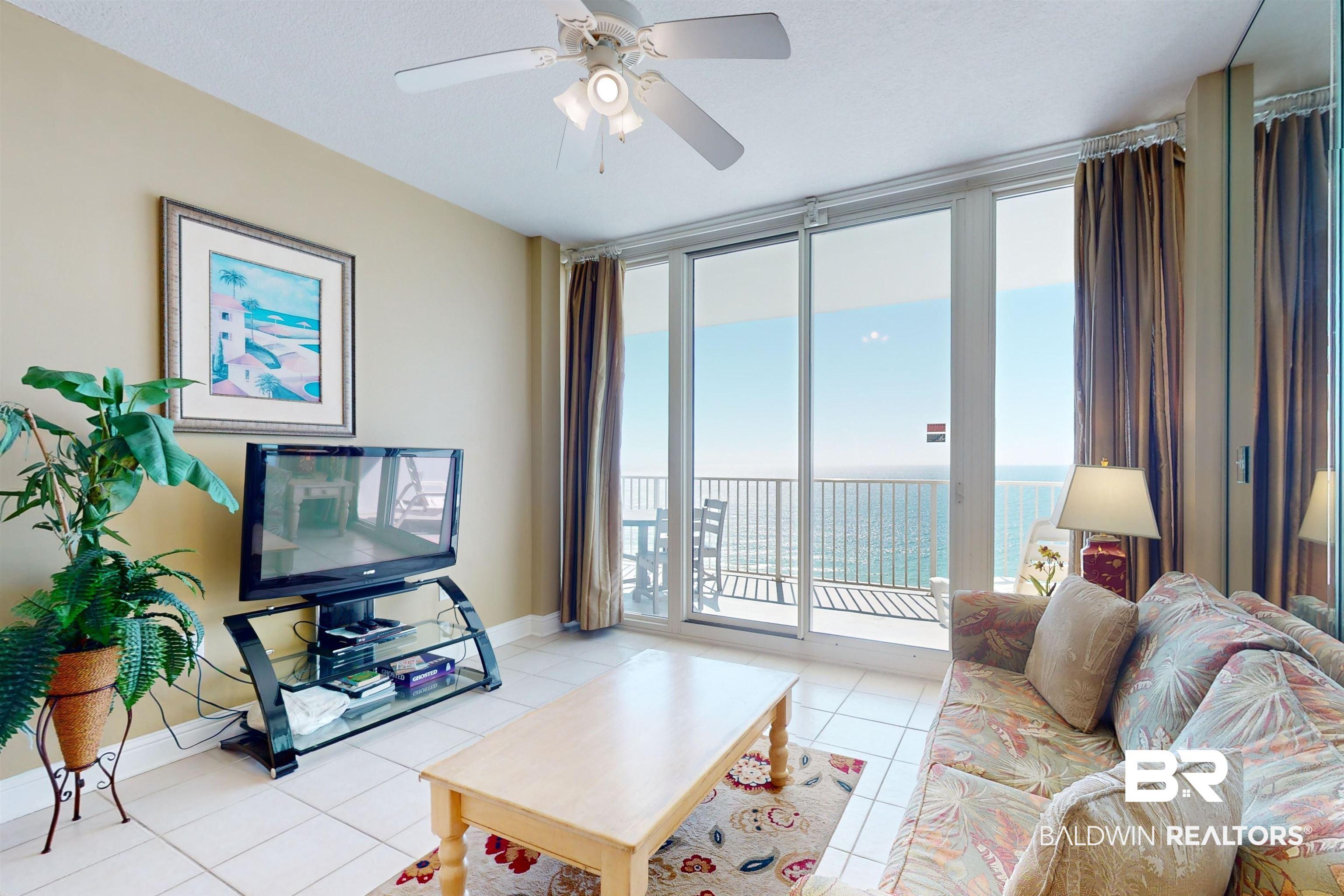 Image 2: Living room with expansive windows, a healthy amount of sunlight, light tile patterned floors, and ceiling fan