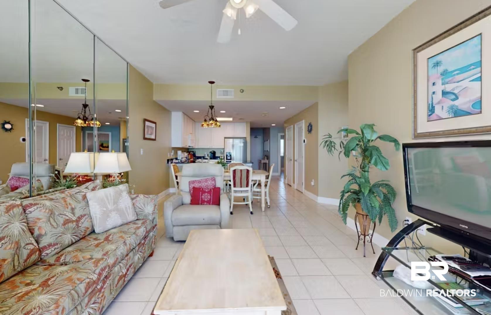 Image 4: Tiled living room featuring ceiling fan with notable chandelier