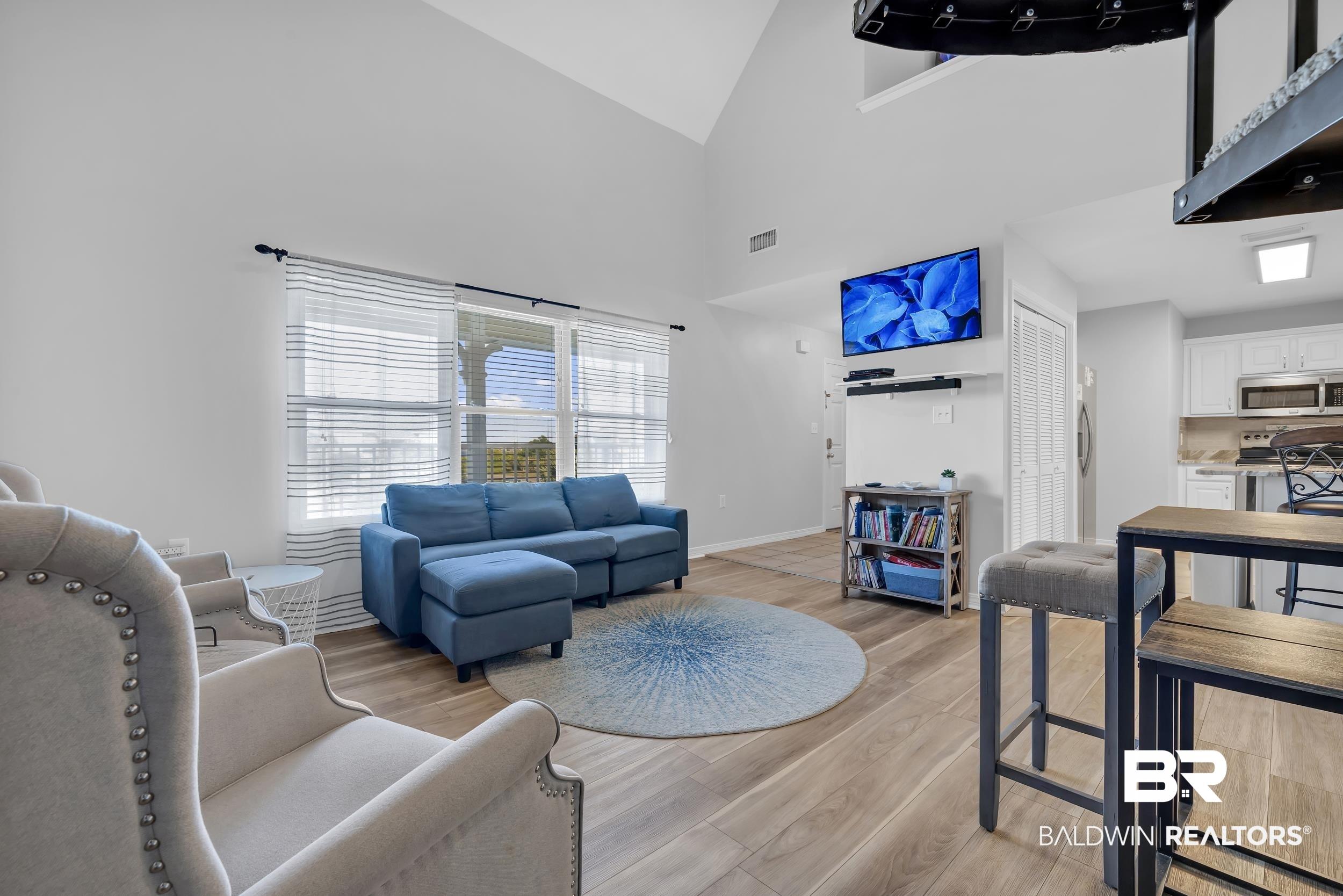 Image 4: Living area with high vaulted ceiling and light wood-type flooring