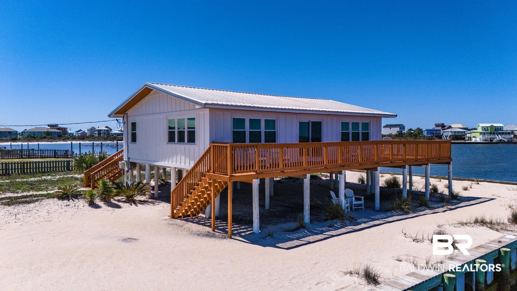 Image 3: Rear view of house with a metal roof and a deck with water view