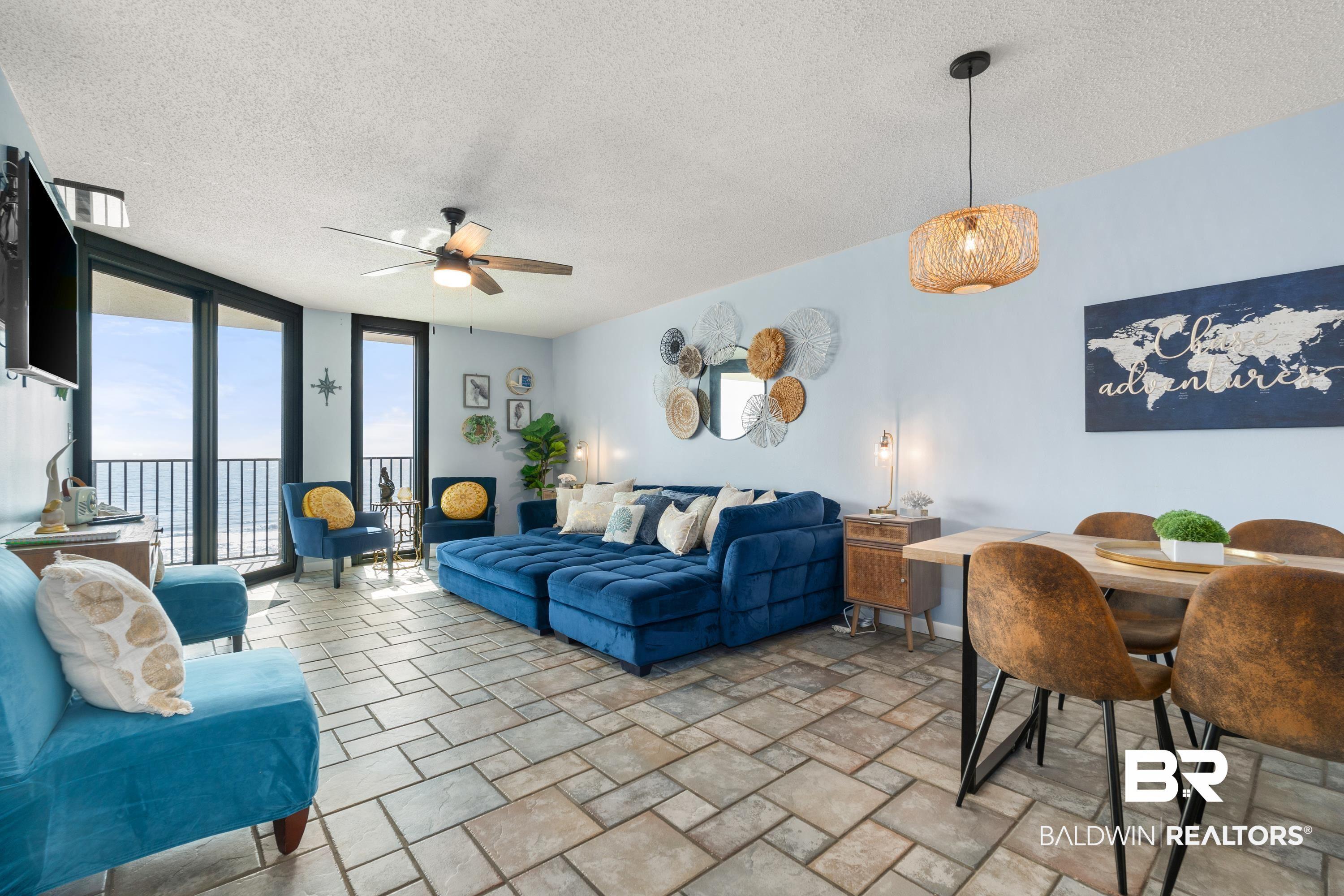 Image 3: Living area with floor to ceiling windows, a textured ceiling, light stone finish floors, and a ceiling fan