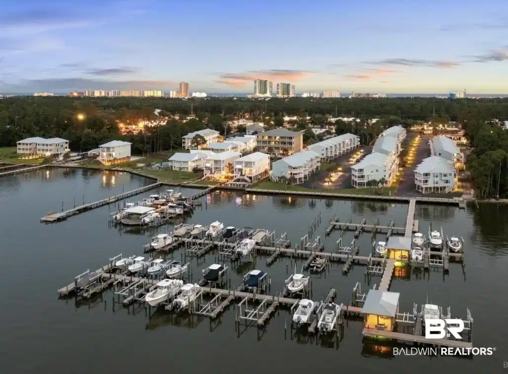 Image 1: Aerial perspective showcasing a marina with multiple boat slips, waterfront residential properties, and distant city skyline