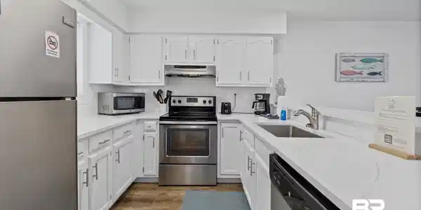 Image 4: Kitchen featuring stainless steel appliances, white cabinets, dark wood-type flooring, light stone counters, and backsplash