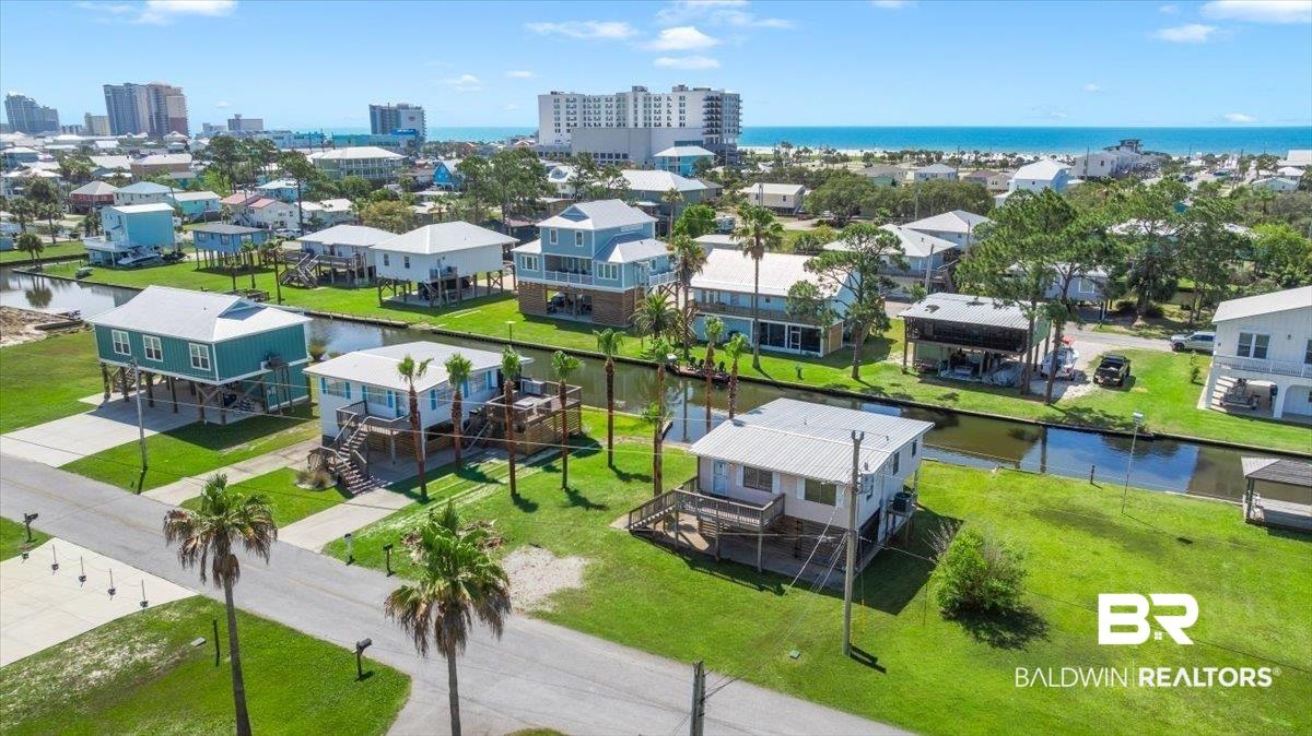 Image 2: Coastal neighborhood with canal access, featuring elevated homes, mature palm trees, and distant ocean views