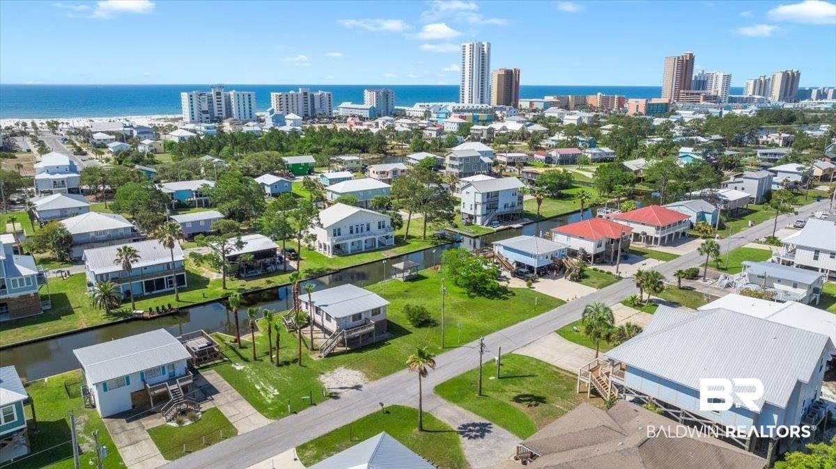 Image 4: Coastal neighborhood featuring canal-front properties, established roadways, mature landscaping, and a distant ocean horizon with a city skyline