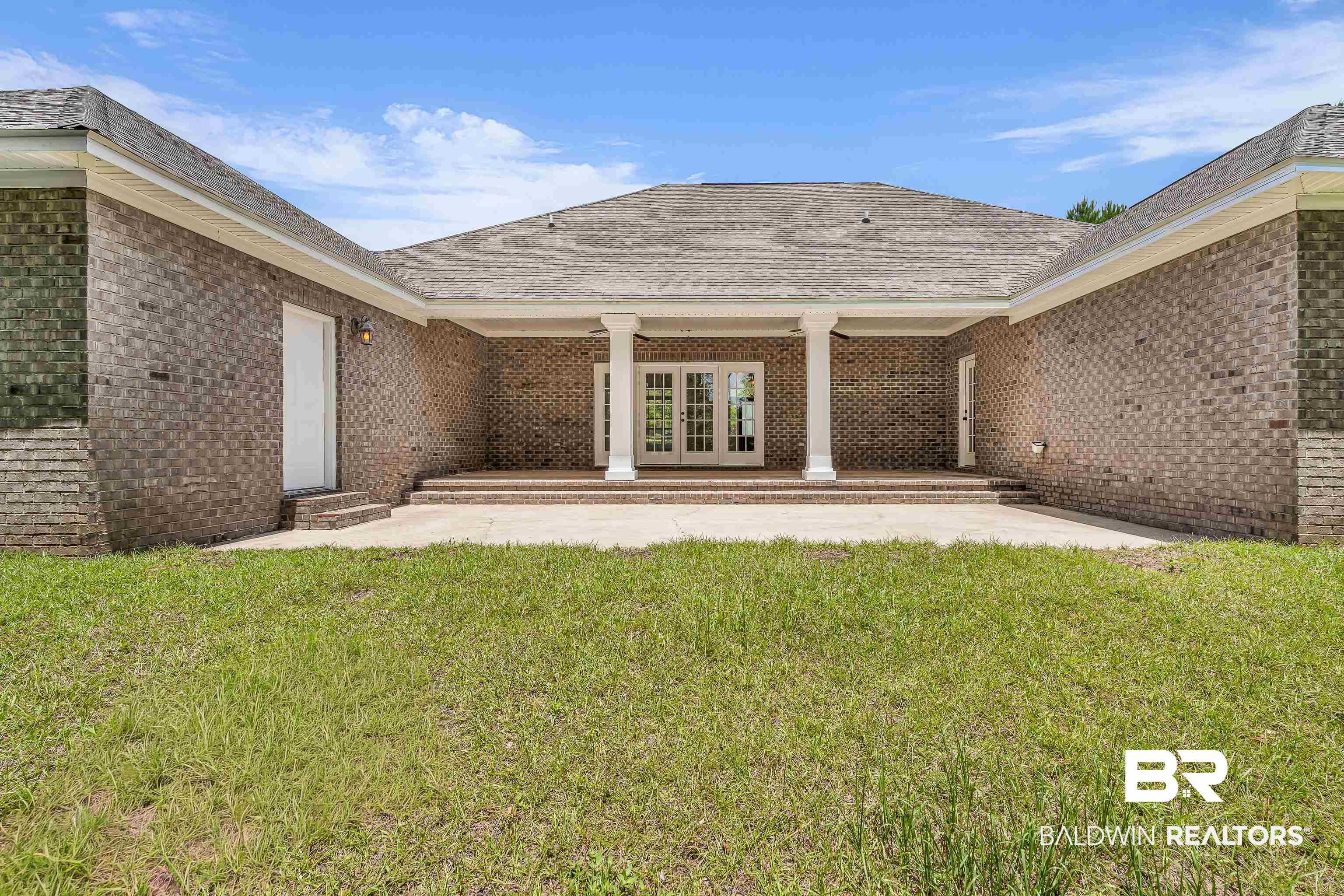Image 4: Rear brick exterior featuring a covered patio with white columns and double French doors