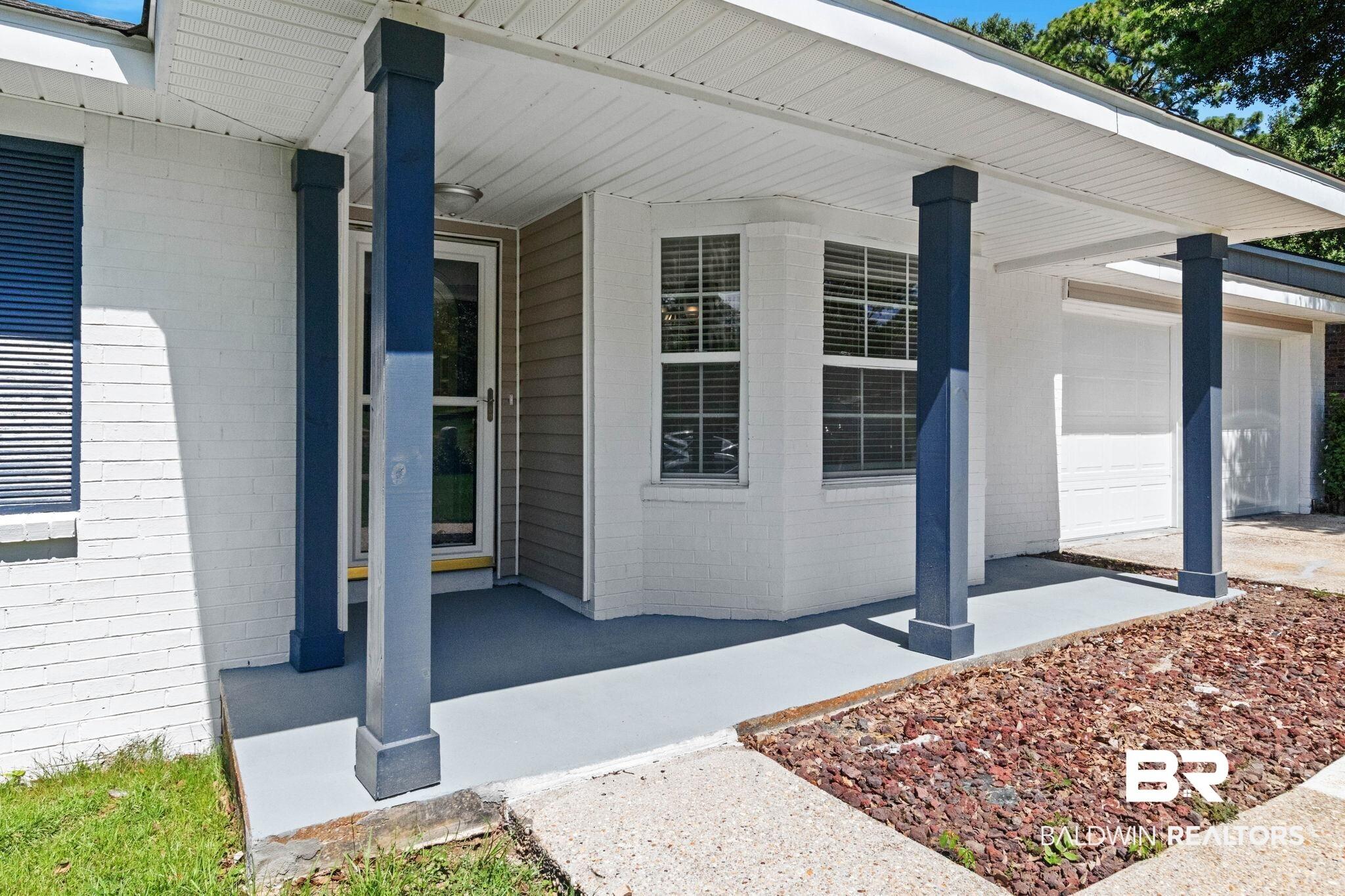 Image 2: Covered entryway featuring blue square columns and a painted concrete porch