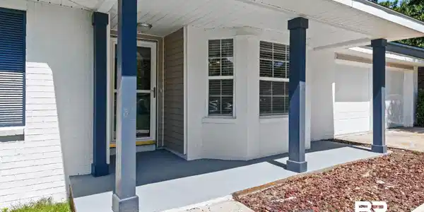 Image 2: Covered entryway featuring blue square columns and a painted concrete porch