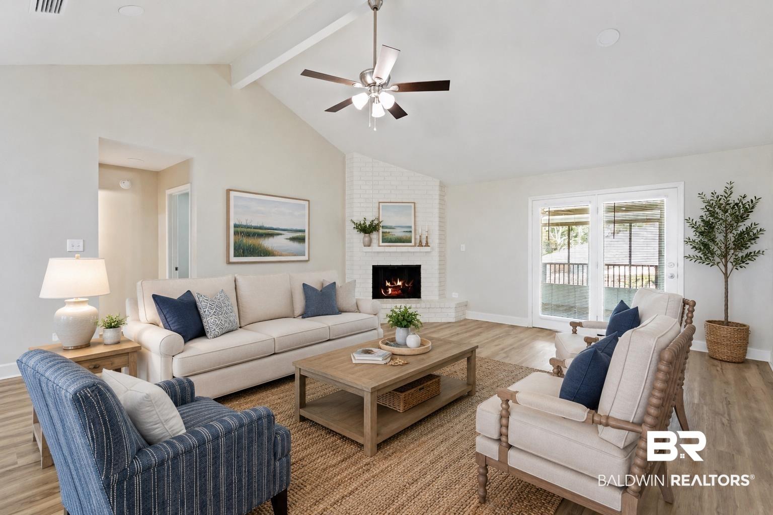 Image 4: Living area with vaulted ceilings, wood-finish flooring, a white brick fireplace, and sliding glass doors