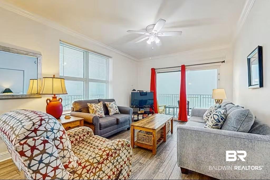 Image 3: Open-concept living area featuring wood-finish flooring, a ceiling fan, and crown molding
