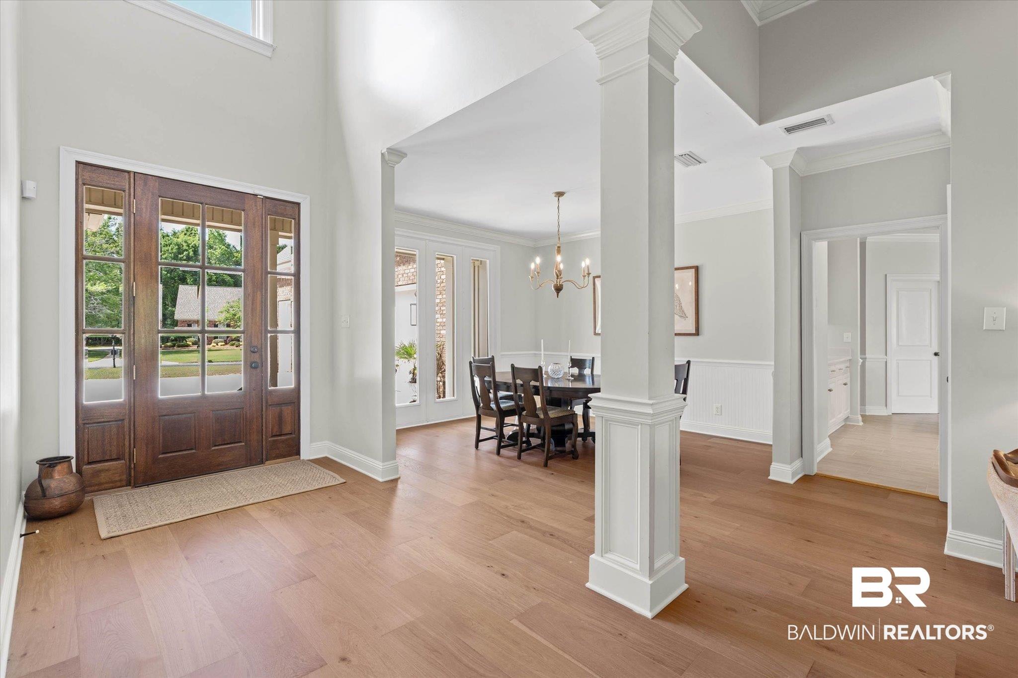 Image 2: Grand foyer with high ceilings, large wood-panel front door with sidelights, and light wood-finish flooring