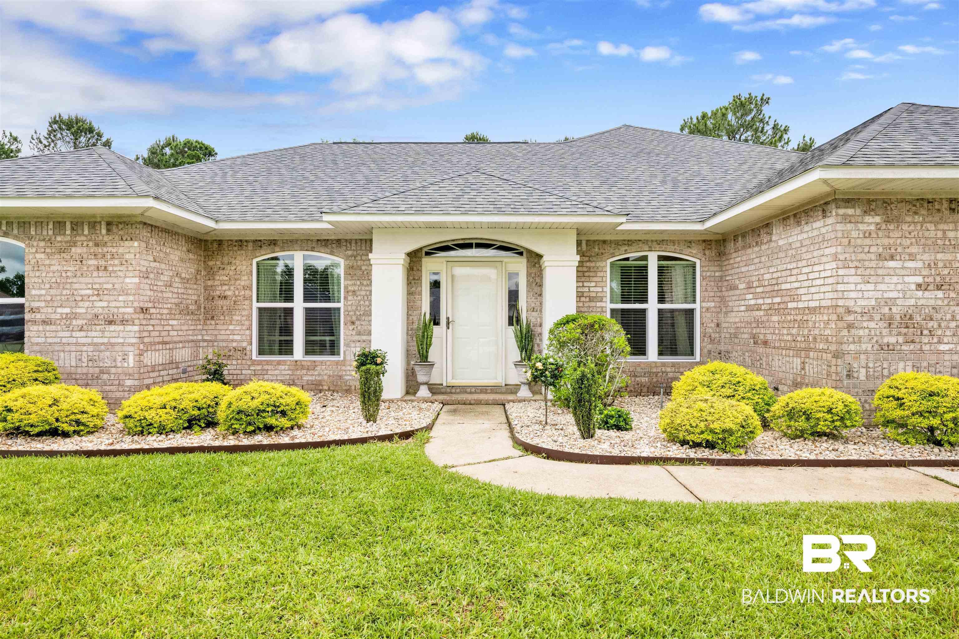 Image 2: Brick exterior featuring arched windows, a covered entry with white columns, and a concrete walkway