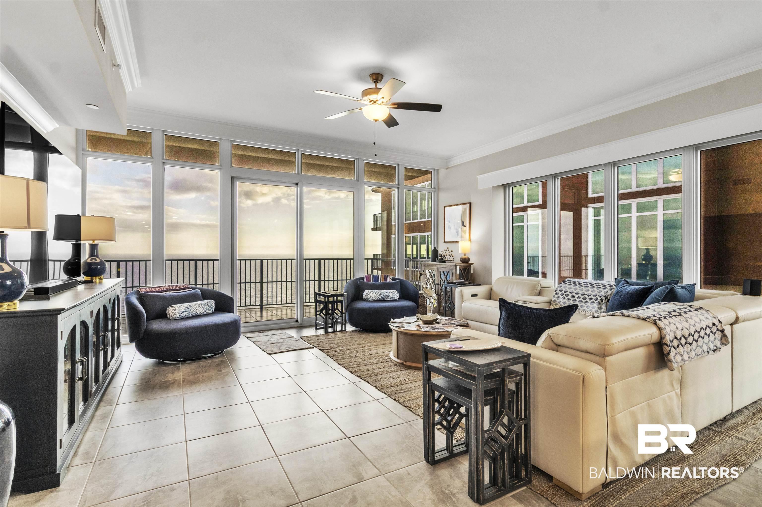 Image 2: Living room with ornamental molding, a ceiling fan, a wall of windows, and light tile patterned floors