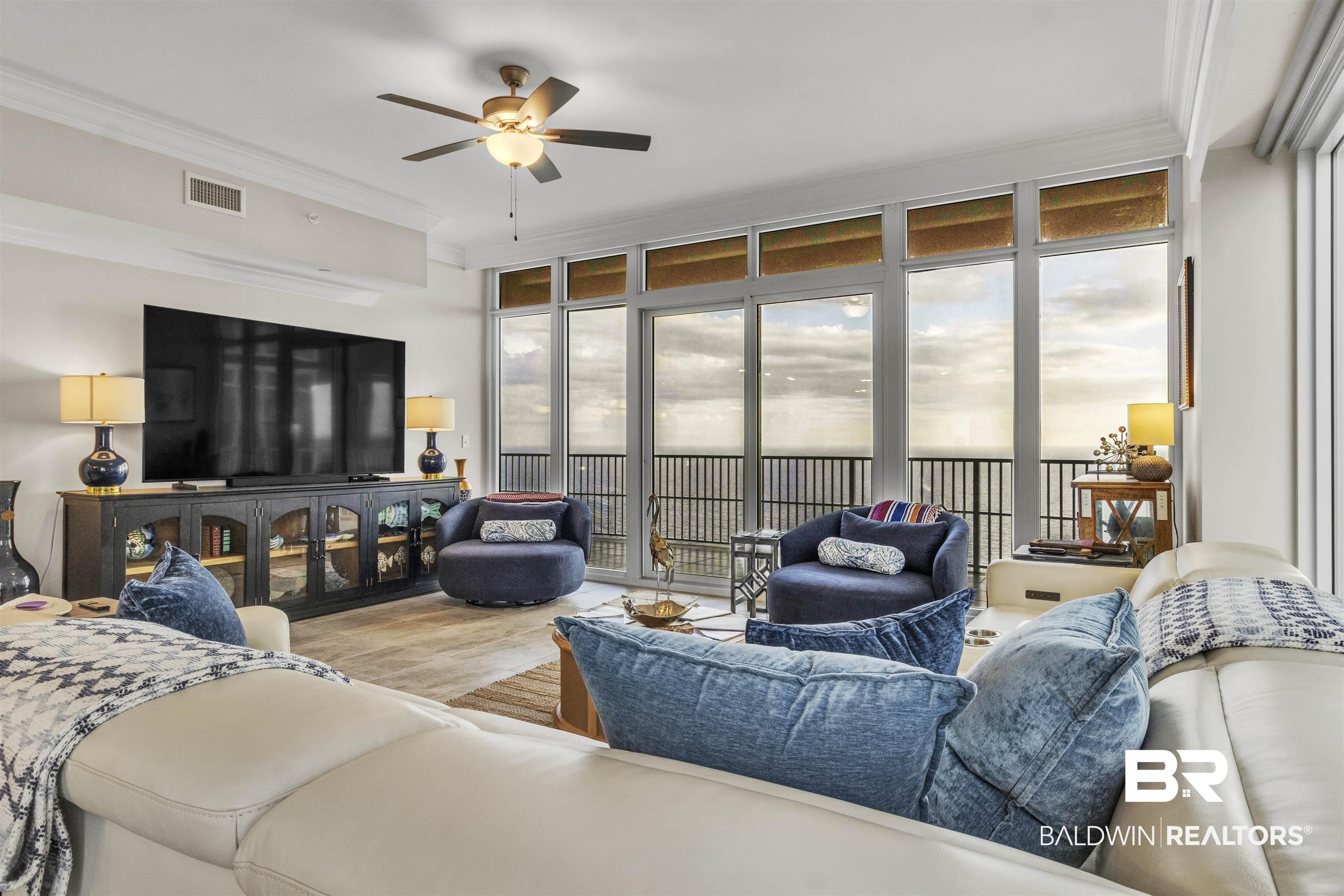 Image 4: Living room with a wall of windows, crown molding, wood finished floors, and a ceiling fan