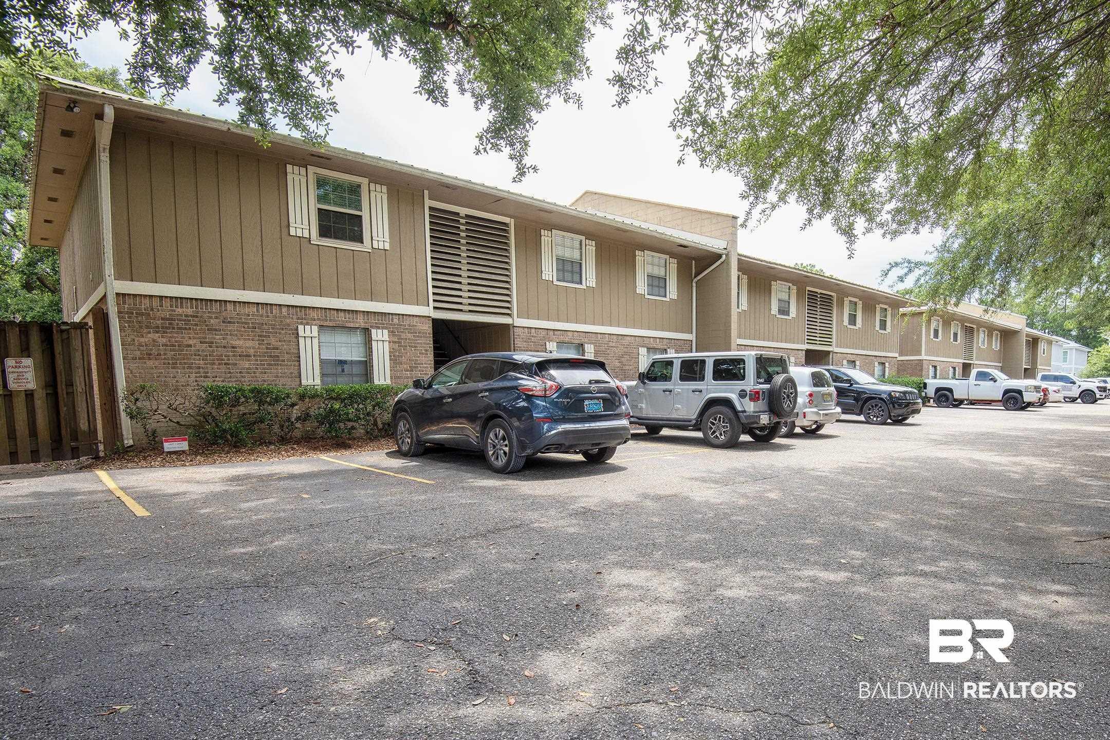 Image 1: Multi-level apartment building featuring a brick facade on the ground level and horizontal siding on upper levels