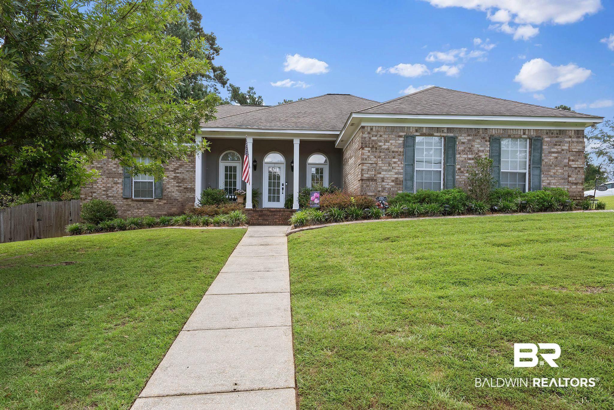 Image 1: Brick exterior with a covered entry featuring white columns and a concrete walkway
